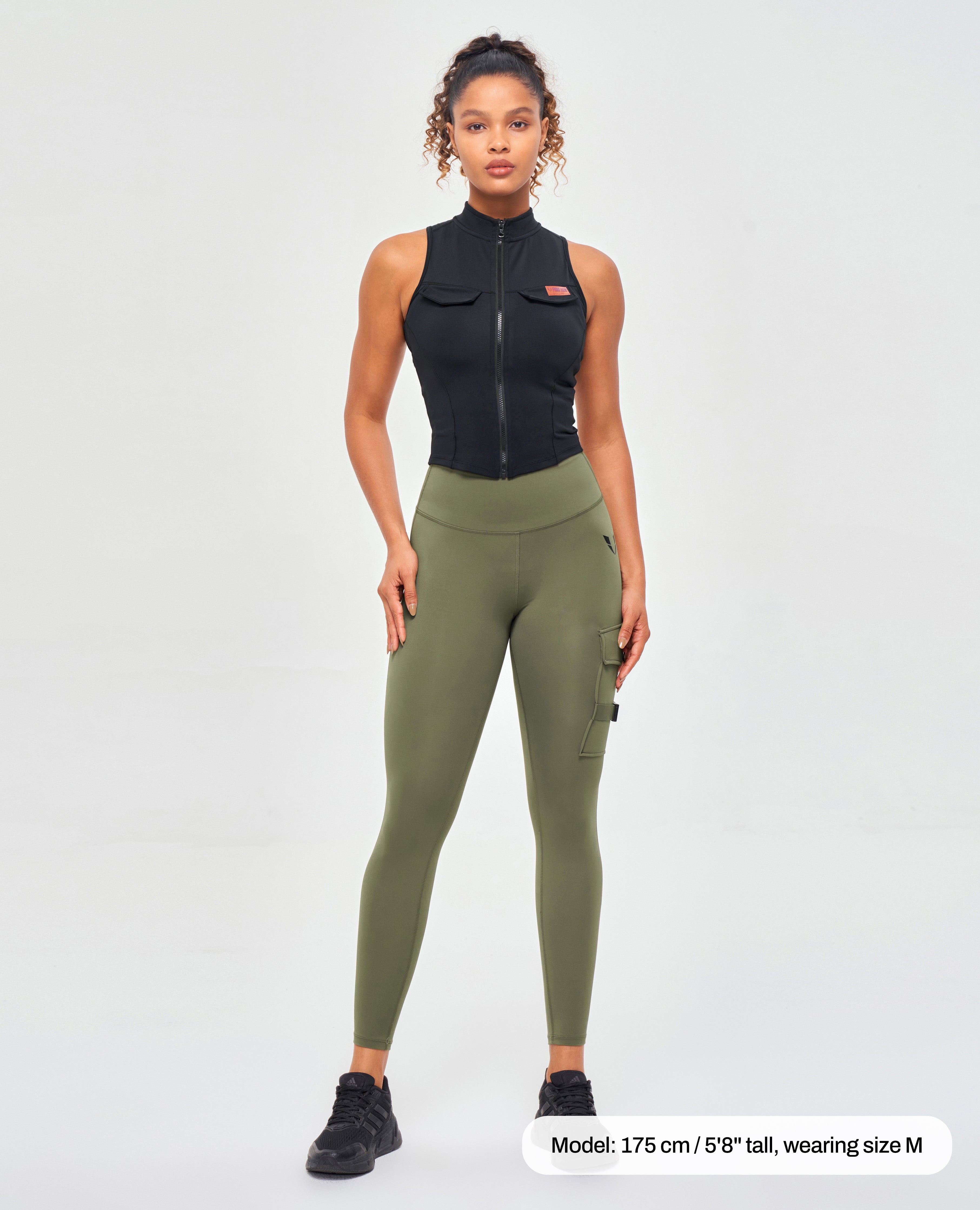 FIRM ABS olive green pocket leggings for fitness with cargo pockets worn by woman with black sleeveless top